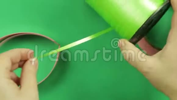 女剪刀在绿色背景上剪绿色丝带视频的预览图