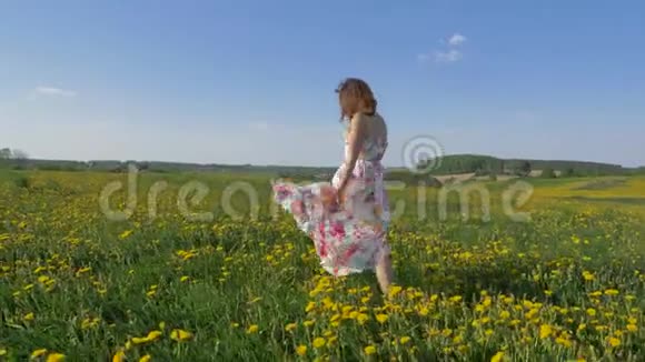 快乐的微笑着的女人穿着漂亮的裙子在盛开的野跳舞视频的预览图
