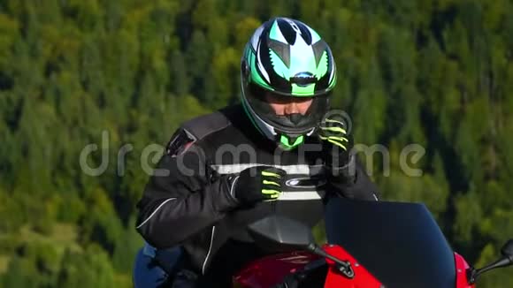 一个骑摩托车的人带着摩托车在山上的年轻帅哥他在休息他喝水视频的预览图
