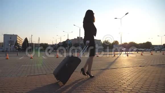 商务女性带着手提箱步行去机场出差穿高跟鞋的女士和她一起视频的预览图