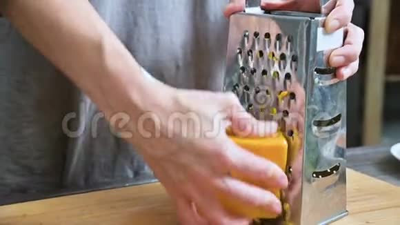 女性手的特写在金属烤架上摩擦奶酪在家庭厨房做饭视频的预览图