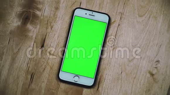 智能手机用铬键旋转绿色屏幕阿尔法视频木制背景上的手机模拟视频视频的预览图