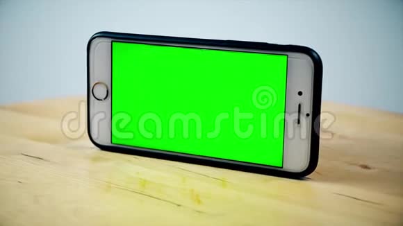 智能手机用铬键旋转绿色屏幕阿尔法视频木制背景上的手机模拟视频视频的预览图