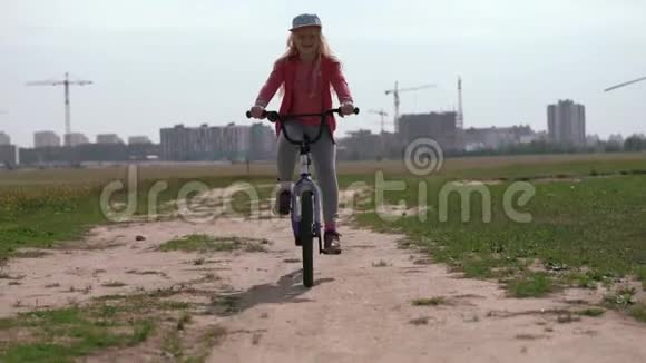 健康的生活方式女孩骑自行车穿过城市附近的田野视频的预览图