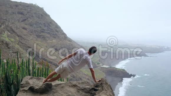 一个人一只手站在山上背对着镜头看着大海沉思着视频的预览图