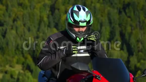 一个骑摩托车的人带着摩托车在山上的年轻帅哥他在休息他喝水视频的预览图