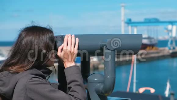 不可辨认的黑发女人透过望远镜看海视频的预览图
