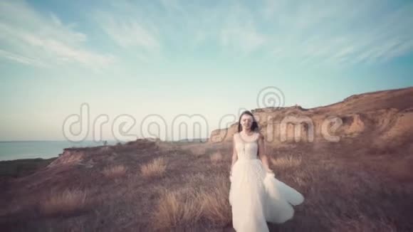 穿着漂亮的长裙子跑新娘穿过风景视频的预览图