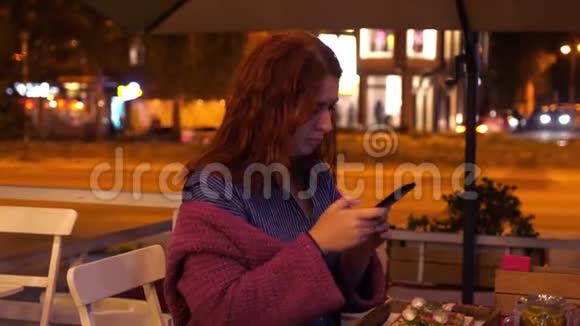 年轻的红海妇女在街边的咖啡馆里在她的食物上拍照灯3840x2160视频的预览图