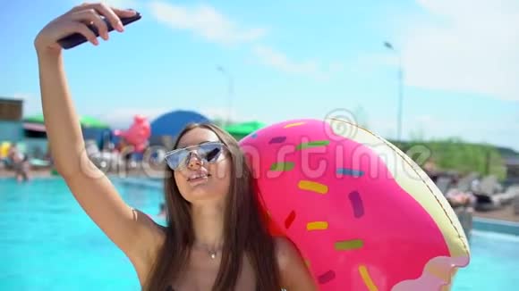 夏天漂亮的年轻女人在智能手机上自拍比基尼女孩在热带游泳池放松这就是视频的预览图