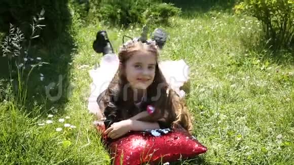 小女孩抱着一个红色的枕头躺在草坪上视频的预览图