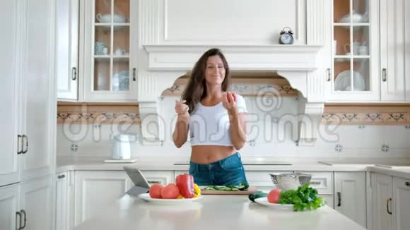 快乐的微笑女人跳舞在家里的厨房里玩番茄视频的预览图