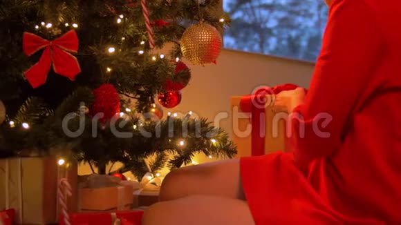 从圣诞树下拿礼物盒的女人视频的预览图