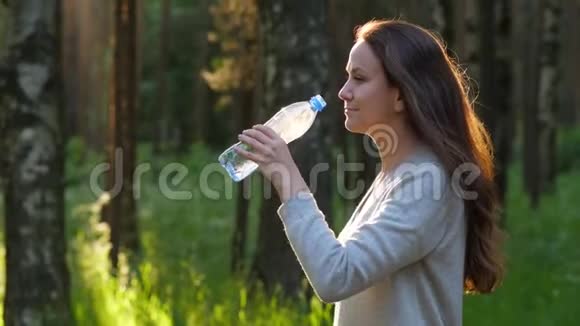 美丽的女人在公园里喝水视频的预览图