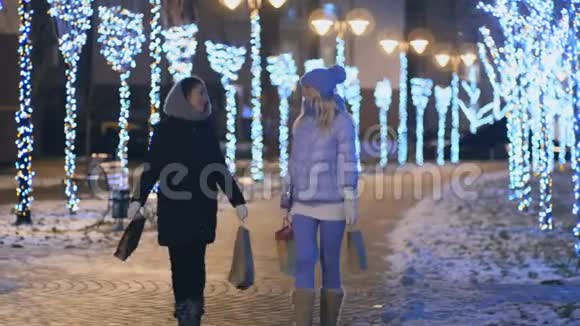 两个女孩带着包裹互相展示礼物晚上在城里散步视频的预览图