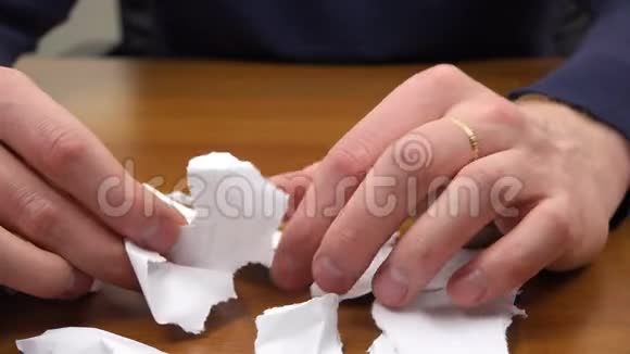 双手穿过桌子上被撕开的纸片视频的预览图