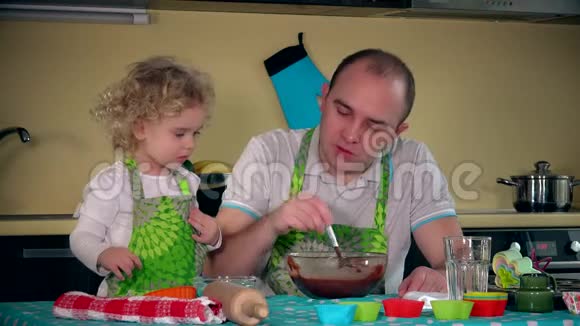 父亲和女儿一起在厨房里加蛋糕面团视频的预览图