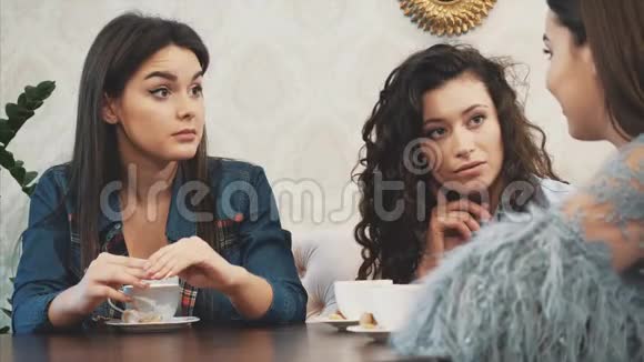 年轻漂亮的女孩坐在咖啡馆里在这段时间里是一勺卡布奇诺享受一种愉快的咖啡味道视频的预览图