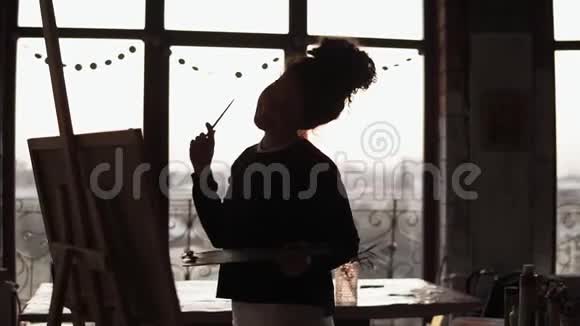 年轻甜美的女艺术家手里拿着颜料调色板在阁楼上翩翩起舞视频的预览图
