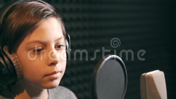 一个男孩正在录音室录制一首歌耳机里的那个男孩视频的预览图