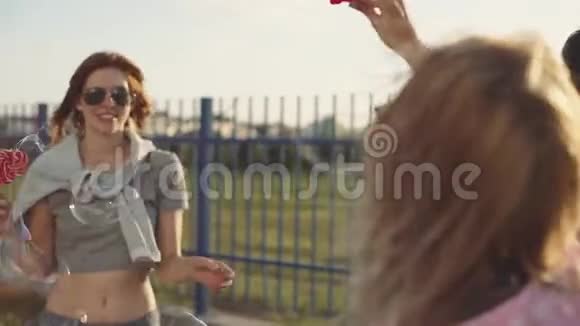 三个朋友在街上玩得开心在日落时做肥皂泡吃棒棒糖视频的预览图