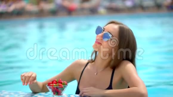 夏天美丽的年轻女子女人喝新鲜鸡尾酒吃草莓比基尼女郎的脸视频的预览图