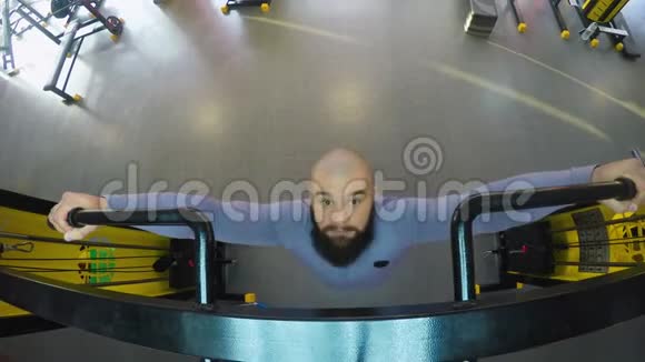 秃头大胡子的男人在健身房里拉着自己热身和肌肉运动视频的预览图