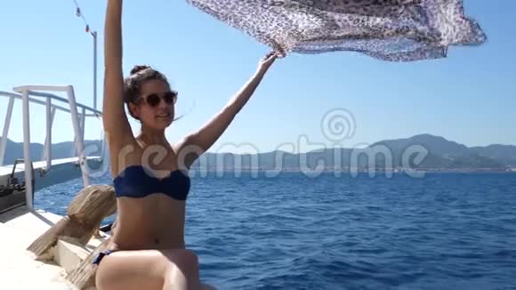 夏天的娱乐活动穿着泳衣和太阳镜的迷人女孩坐在船头的游艇上在大海和布蝇中休息视频的预览图