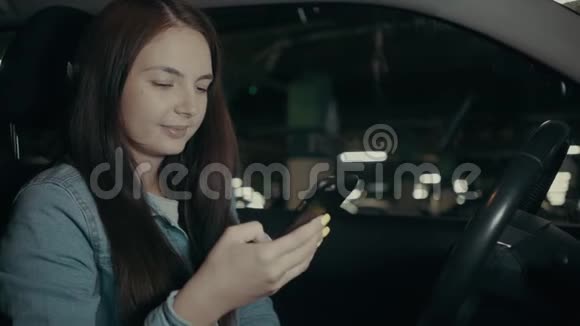 女人坐在停车场的车里用手机申请视频的预览图