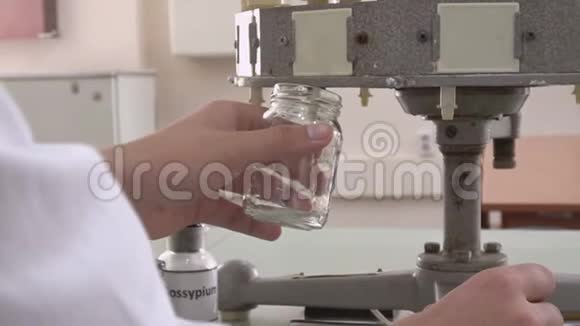 一个穿白色工作服的人用清澈的液体装满容器在实验室工作的化验师视频的预览图