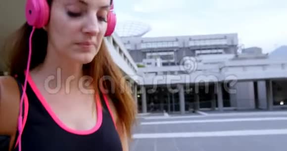 城市里的女街舞女用耳机听音乐视频的预览图
