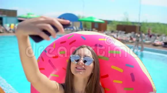 夏天漂亮的年轻女人在智能手机上自拍比基尼女孩在热带游泳池放松这就是视频的预览图