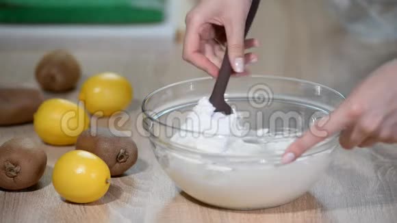 女性手将玻璃碗中的奶油与刮刀混合视频的预览图