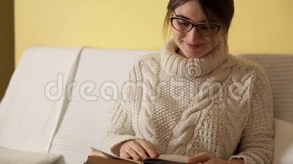一个冬天的晚上在家里穿着温暖舒适的毛衣的小女孩戴着眼镜看书睡着了房子视频的预览图