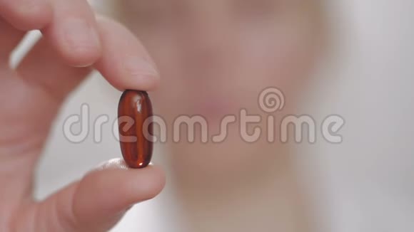 女人拿出一块药片用手指拿着它然后吞下它用水喝它视频的预览图