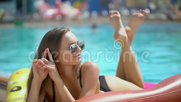 夏天美丽的年轻女子比基尼女孩在热带游泳池放松夏日的女孩坐在户外视频的预览图