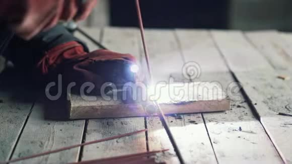 特写焊工焊接两个金属件工人在室内工作动作缓慢视频的预览图