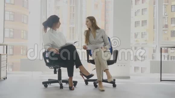 办公室工作人员两名妇女坐在椅子上交谈其中一名妇女讲述另一名妇女的工作视频的预览图