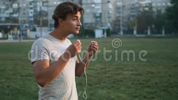 年轻健康的混合种族男子听音乐通过在城市体育场跑道上跑步锻炼身体视频的预览图