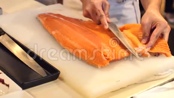寿司厨师的特写展示了一个的能力切片新鲜鲑鱼在寿司吧视频的预览图