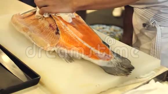 寿司厨师的特写展示了一个的能力切片新鲜鲑鱼在寿司吧视频的预览图