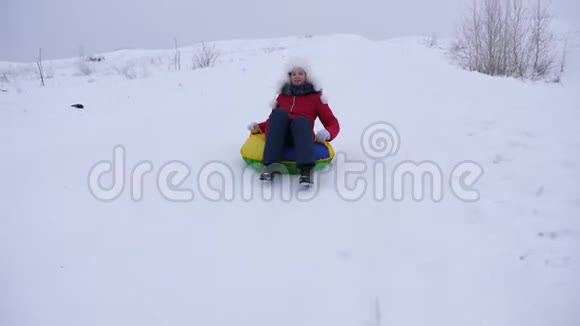 女孩在冬天滑雪从高山雪橇和充气雪管少女在冬季公园玩耍视频的预览图