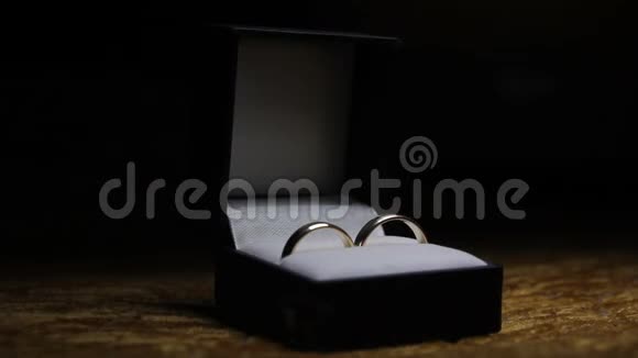 深色背景下红色黑色盒子的结婚戒指带有移动的光线视频的预览图
