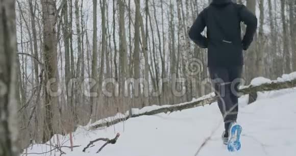 阳光明媚的冬天早晨一对年轻健康的年轻夫妇带着运动服在森林里奔跑跳跃视频的预览图