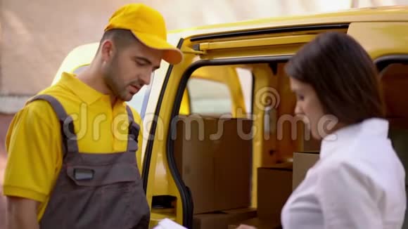 女商人在他的车附近的室外检查由黄色制服的快递员送货视频的预览图