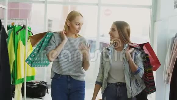 两个女朋友正慢慢地穿过宽敞的精品店他们拿着无数的纸袋聊天视频的预览图