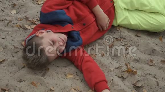 哭泣的小男孩躺在沙滩上视频的预览图