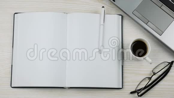 白色办公桌上的笔记本电脑日记眼镜和咖啡杯上景视频的预览图