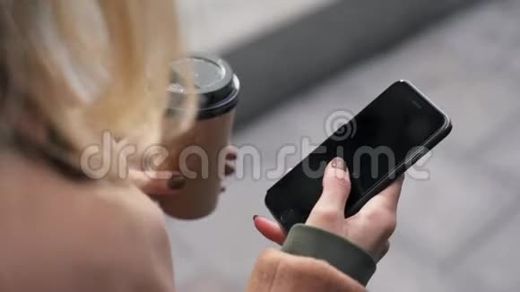 手拿咖啡在智能手机屏幕上滑动视频的预览图