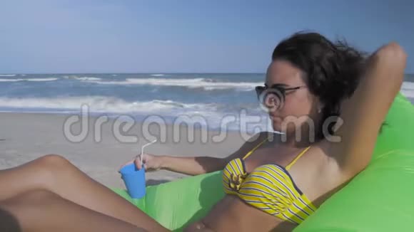 特写镜头美丽的女士戴着太阳镜在海边休息喝一杯鸡尾酒视频的预览图